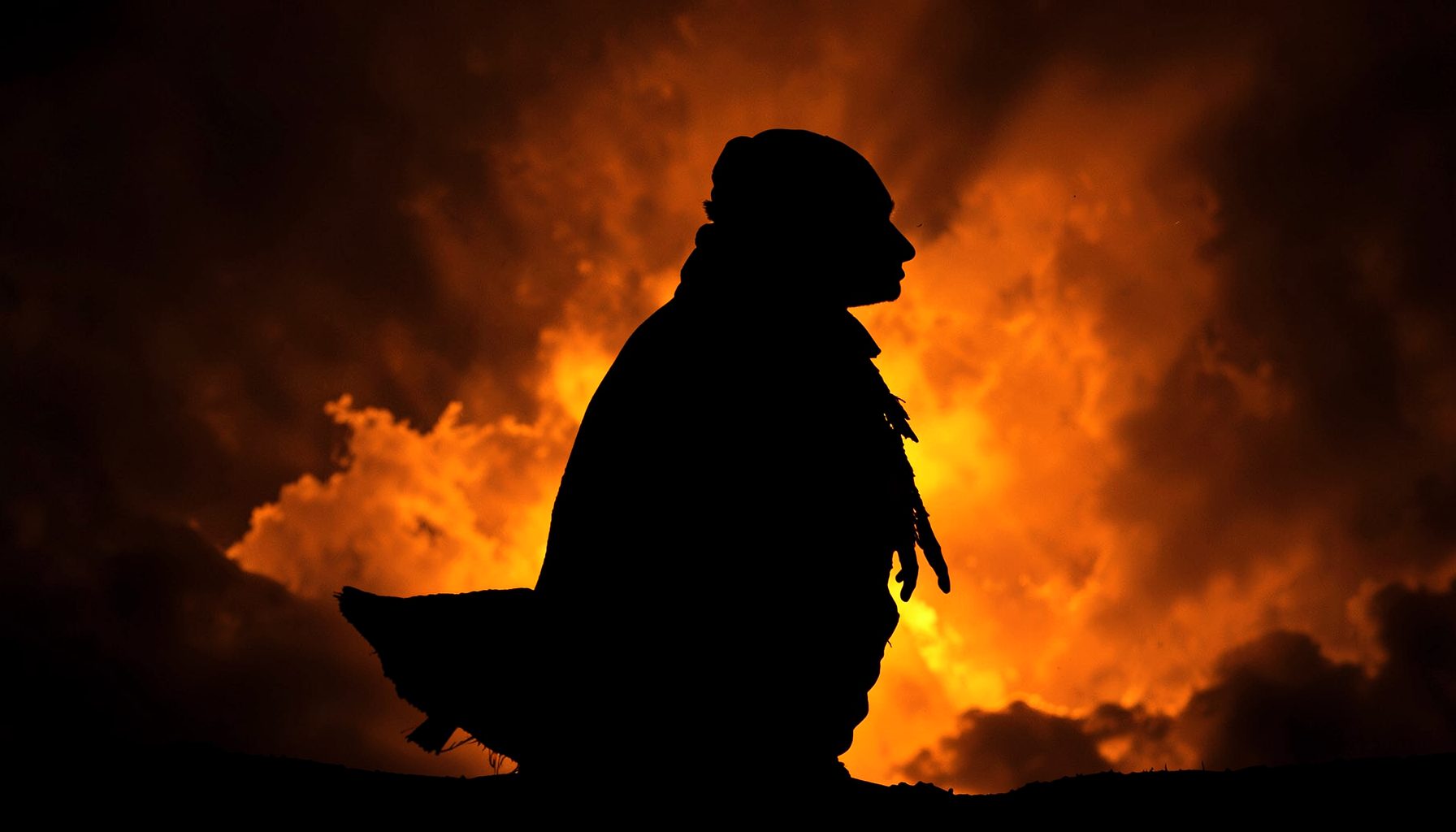 A character-themed desktop wallpaper with a dramatic silhouette against a fiery orange and dark background